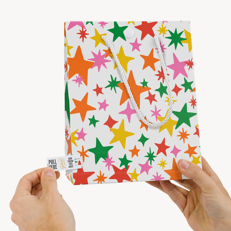 Hands demonstrating Joker Greeting tab removal system on endless mariachi musical gift bag with pull tab clearly visible