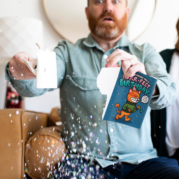Man holding Cool Cat musical birthday prank card with chunky glitter spilling everywhere showing glitter defense system in action by Joker Greeting