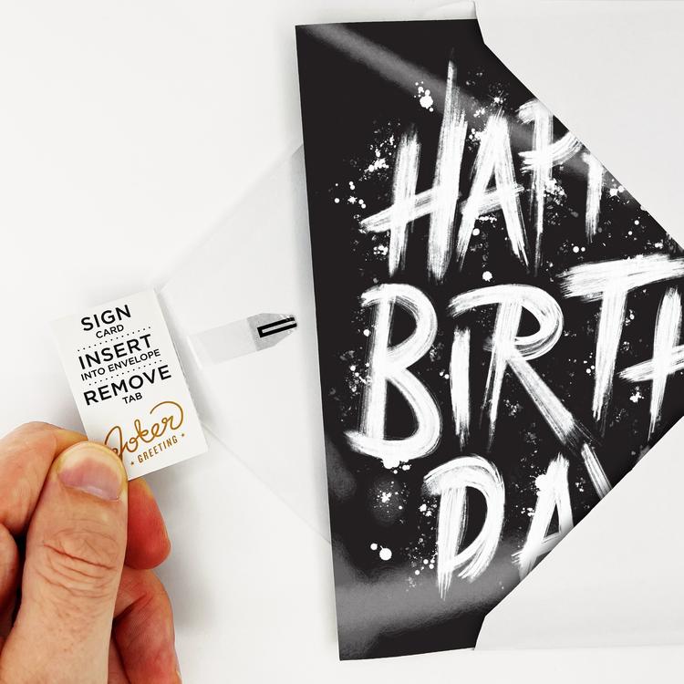 Card with Tab Demonstration:
Hand demonstrating Birthday Screamer musical prank card with Joker Greeting instruction tab showing Sign Card Insert Into Envelope Remove Tab activation process