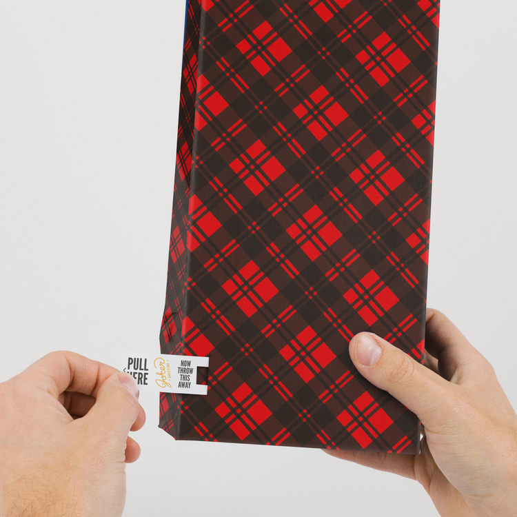 Hands demonstrating tab removal system on endless meowy Christmas bottle bag with red and black plaid pattern from Joker Greeting collection