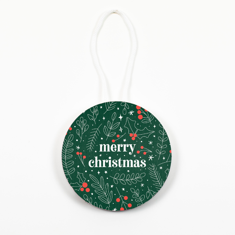 A round ornament with a green background featuring a festive pattern, including 'merry christmas' text and decorative elements. A string for hanging is visible at the top.