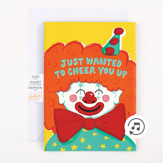 A greeting card with an illustration of a smiling clown with red hair and a red bow tie, wearing a party hat, against a yellow background. The text on the card reads 'JUST Wanted TO CHEER YOU UP'.