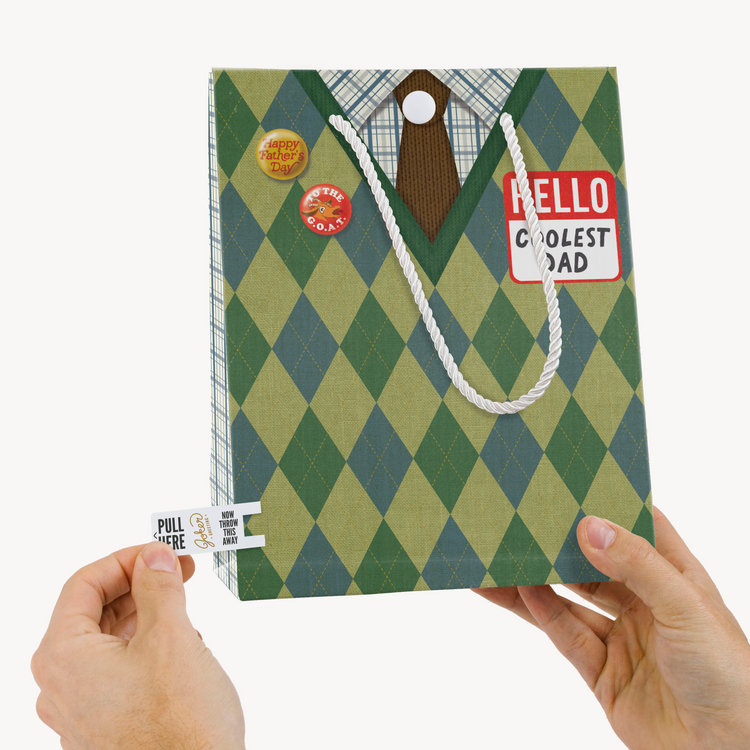 Hands holding Father's Day G.O.A.T musical gift bag with pull tab - Joker Greeting endless music activation system