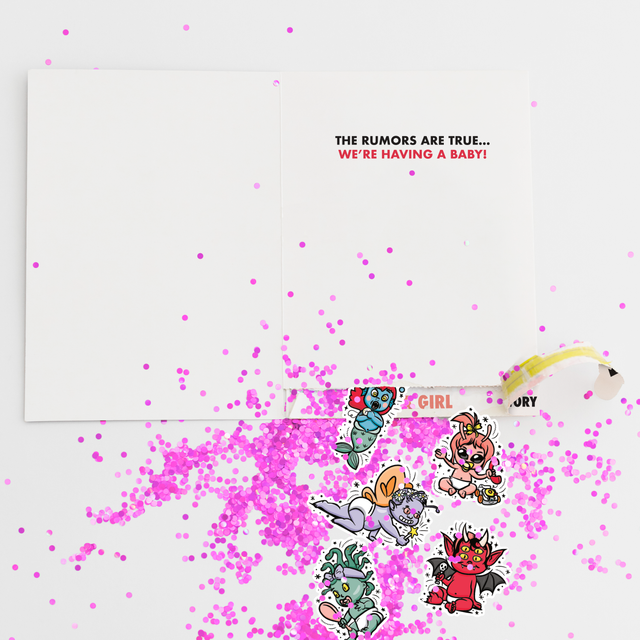 Gender reveal girl prank card with pink glitter and cartoon character stickers scattered around newspaper-style greeting card