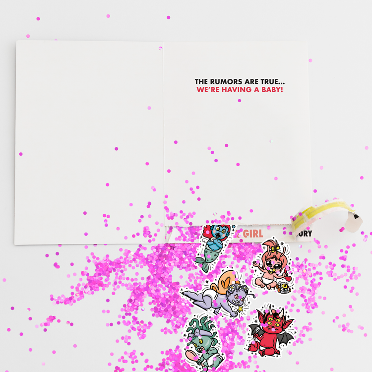Gender reveal girl prank card with pink glitter and cartoon character stickers scattered around newspaper-style greeting card