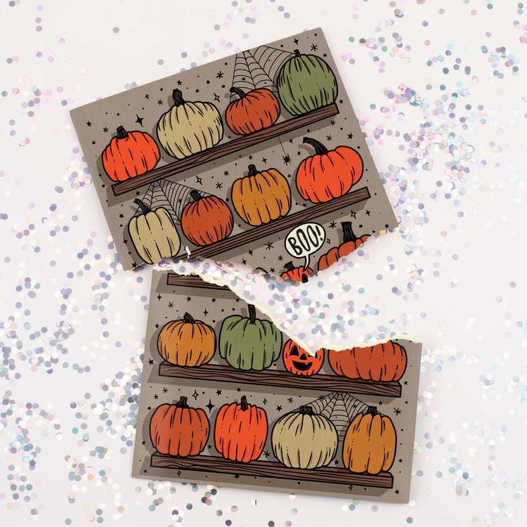 Halloween pumpkin greeting card surrounded by large holographic glitter pieces scattered across surface showing glitter surprise feature