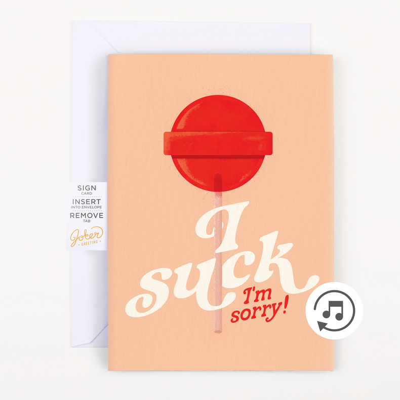 A greeting card with a graphic design showing a red lollipop with the text 'I suck, I'm sorry!' on an orange background. A plain white envelope is included.