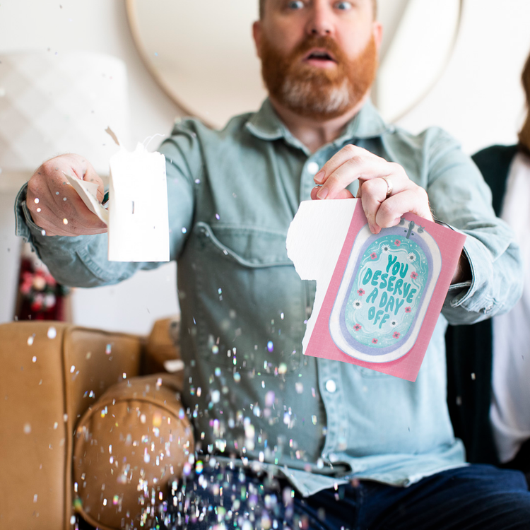Bearded man holding you deserve a day off musical Mother's Day card with large glitter explosion showing activated prank greeting card with bathtub design