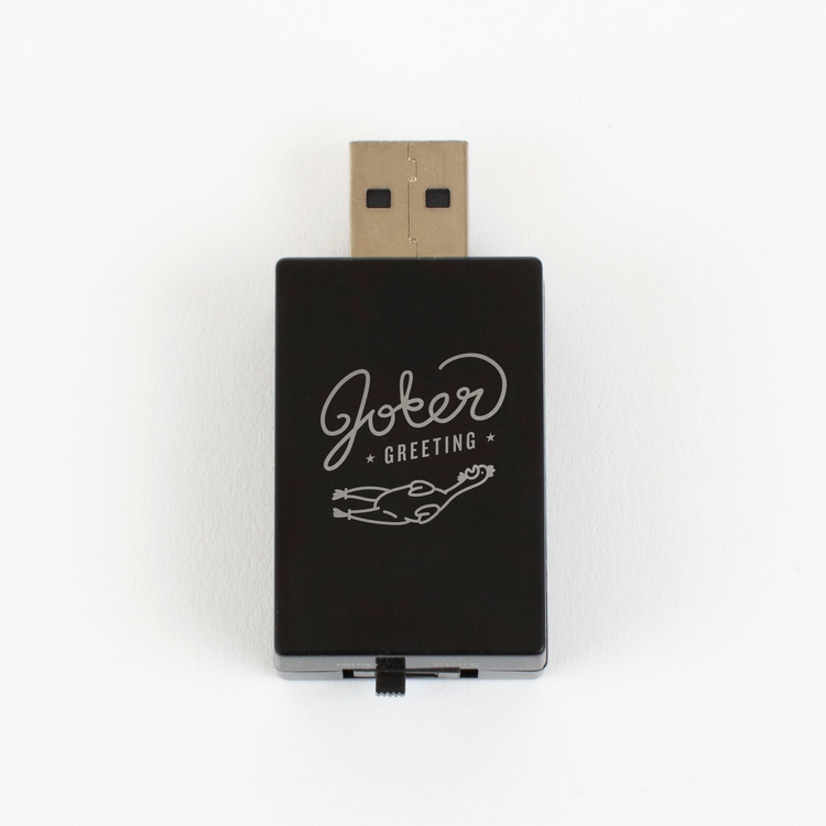 Black USB rubber chicken sound device with Joker Greeting logo and chicken icon showing USB Type-A connector for computer pranks