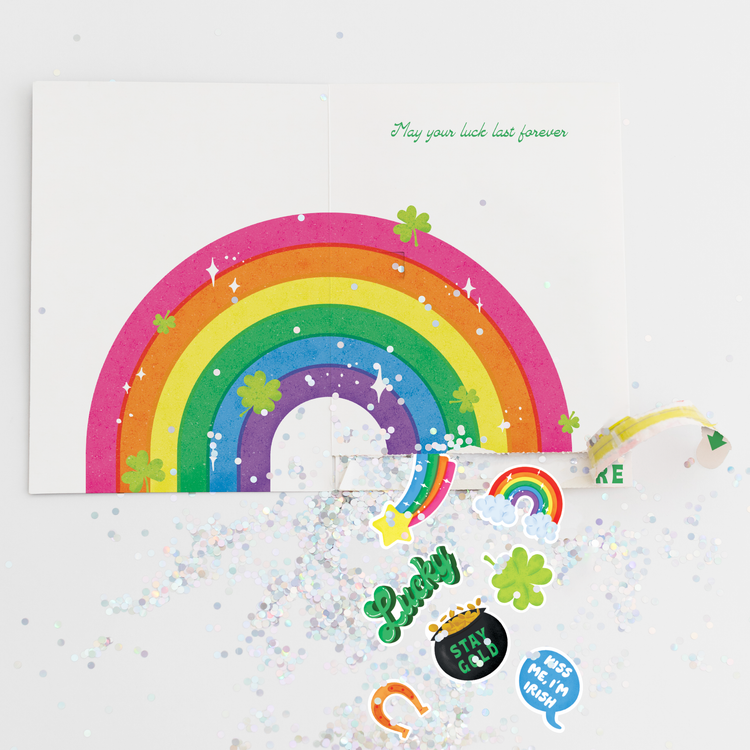 St. Patrick's Day prank card opened showing rainbow, glitter stickers including Lucky text, pot of gold, and Kiss Me I'm Irish phrases