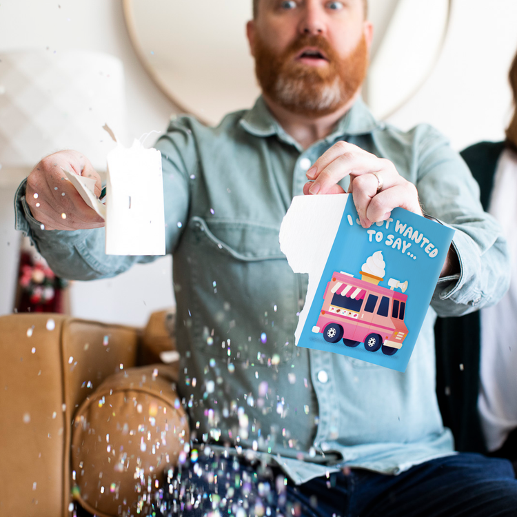 Person holding torn ice cream musical greeting card with surprised expression as glitter falls around them