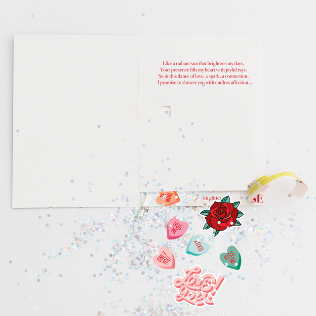 Opened Joker Greeting endless musical Valentine card showing large glitter and romantic heart stickers scattered around with love-themed designs  "Hug Me," "Only You," "Kiss Me," and "Love You."