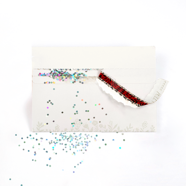 (Envelope being opened with glitter spilling): Floral design glitter trap envelope being opened with colorful glitter spilling out creating elegant prank surprise