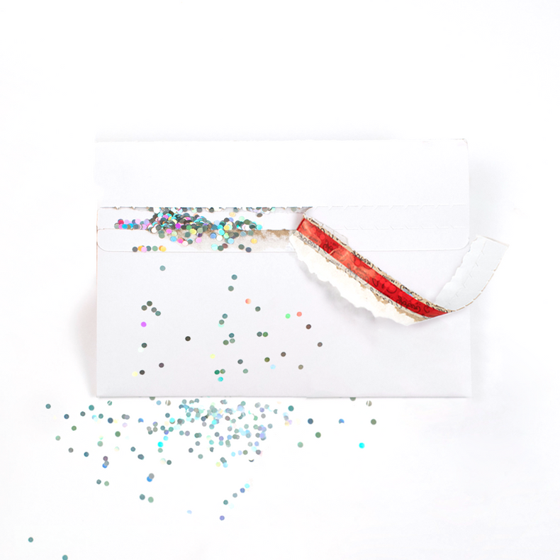 Opened Joker Greeting White glitter trap envelope with large glitter scattered around showing activated glitter surprise mechanism