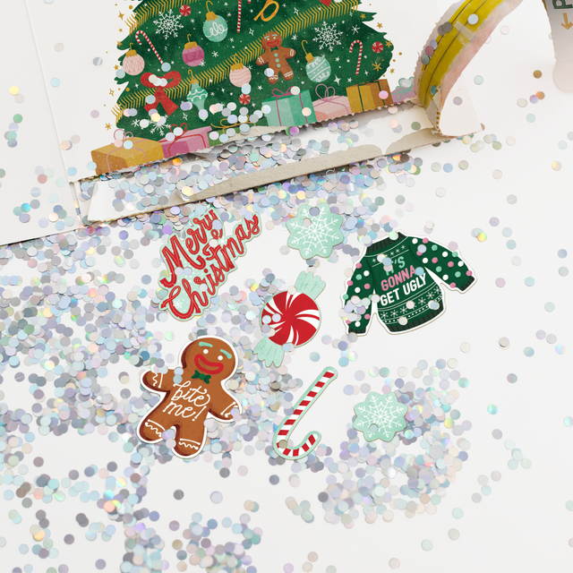  Christmas pull surprise card opened showing large colorful glitter spill and festive stickers including gingerbread man candy cane and ugly sweater designs