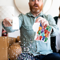 Person holding activated Joker Greeting congratulations card with large glitter falling and surprised expression showing endless musical prank in action