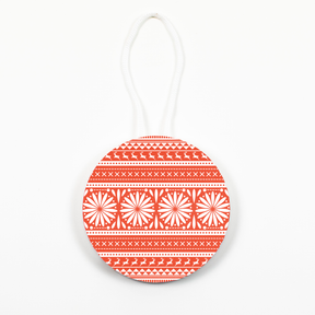 A round Christmas ornament with a geometric pattern in red and white, with a hanging loop at the top.