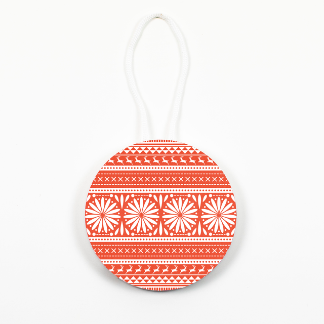 A round Christmas ornament with a geometric pattern in red and white, with a hanging loop at the top.