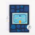 A graduation-themed greeting card with 'YOU DID IT' text, graduation cap illustrations, and various supportive messages in speech bubbles. The card also features a small envelope and a 'This card plays an off-tune Graduation song with a flute' note.