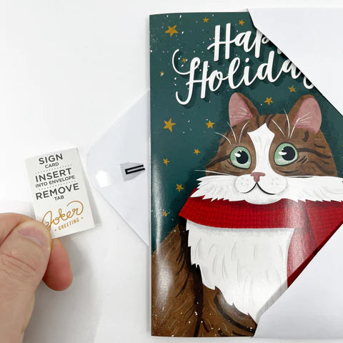 Hand holding Joker Greeting Happy Holidays musical card showing removal tab activation system for endless Christmas music