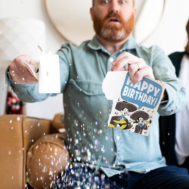 Glitter Action Shot:
Man holding Mariachi Happy Birthday musical prank card with chunky glitter spilling everywhere showing mariachi band illustration and glitter defense system by Joker Greeting