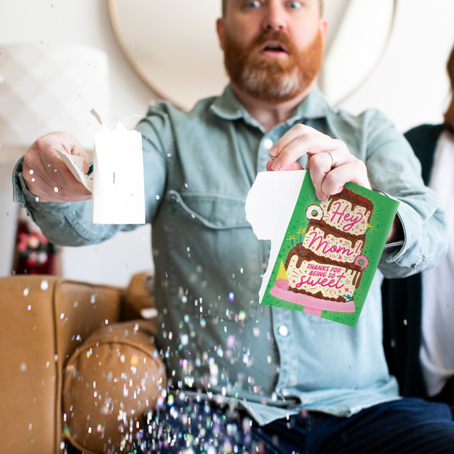  Person holding torn musical Mother's Day card with surprised expression as large glitter falls around them demonstrating glitter surprise activation
