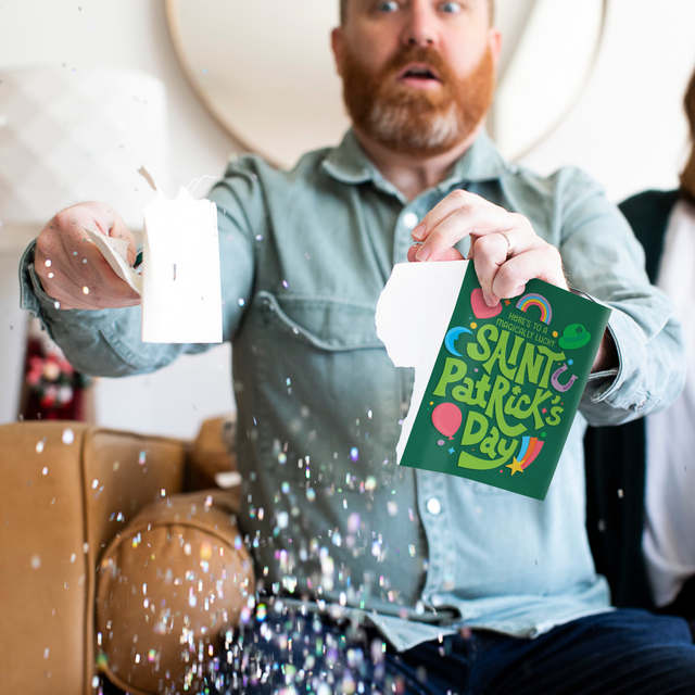 Man ripping St. Patricks Day card opened with glitter falling around it