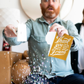  Person holding torn Golden Girls musical greeting card with confetti falling and surprised expression