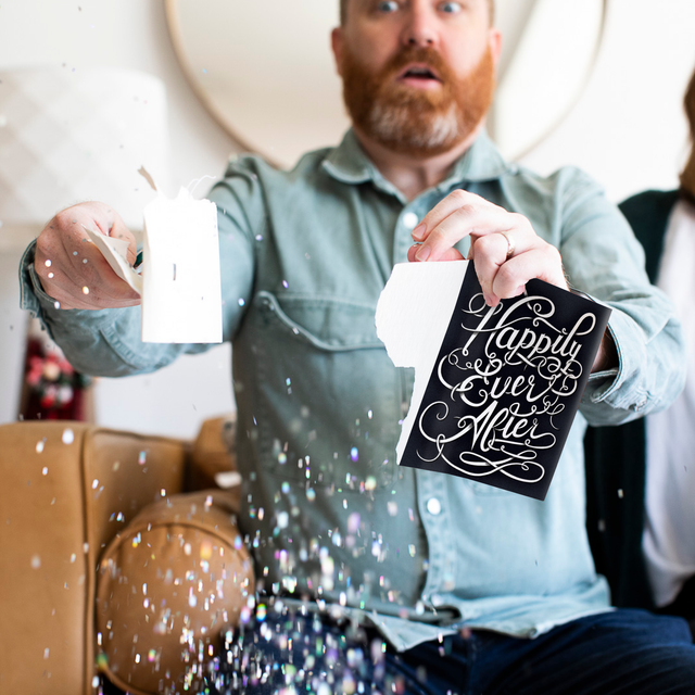 Man holding opened Joker Greeting endless musical wedding card with large glitter explosion effect and surprised facial expression